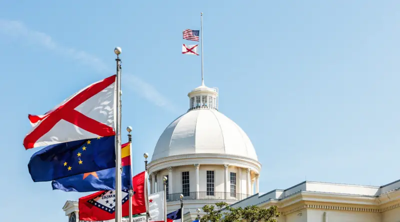 The dome of the Alabama State Capitol building flanked with various flags.