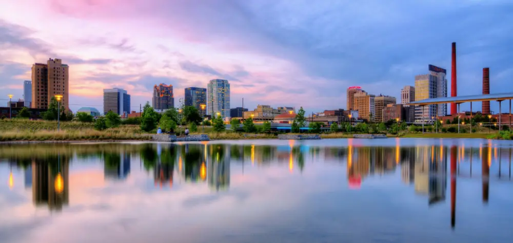 Birmingham, Alabama near sunset showing the city skyline reflected in a small lake at Rail Road Park.
